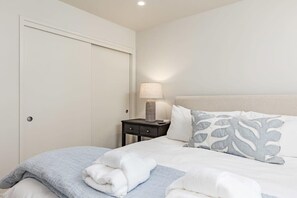 Une chambre d’hôtel avec un lit, une table de chevet avec une lampe et une porte fermée.