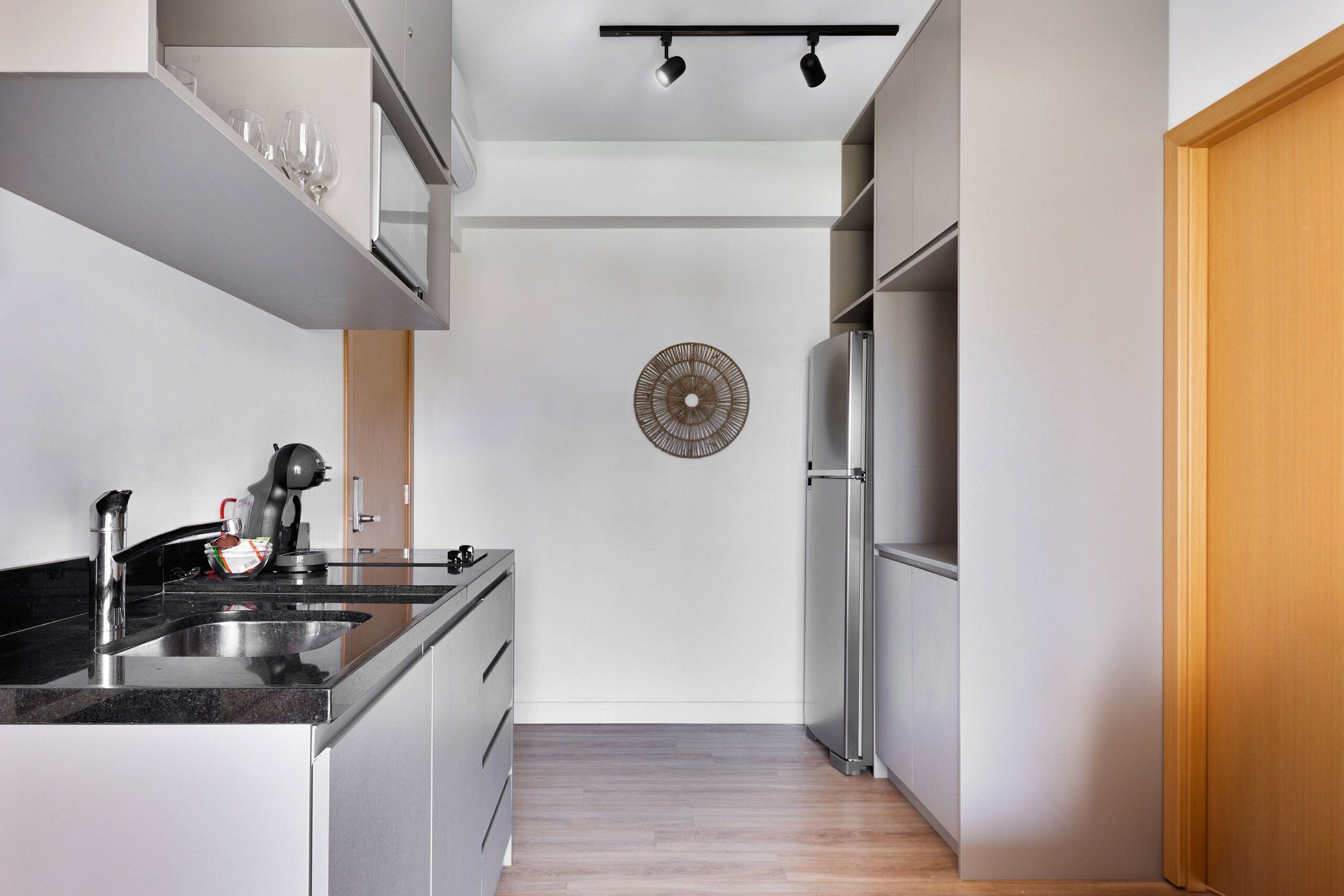 A modern kitchen with a stainless steel refrigerator, a built-in oven, and a black countertop.