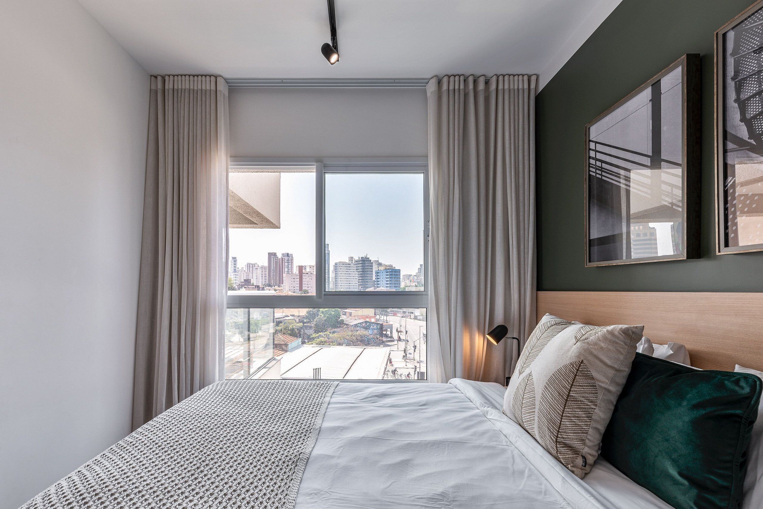 Una habitación de hotel con una cama grande, vista a la ciudad y un cuadro en la pared.