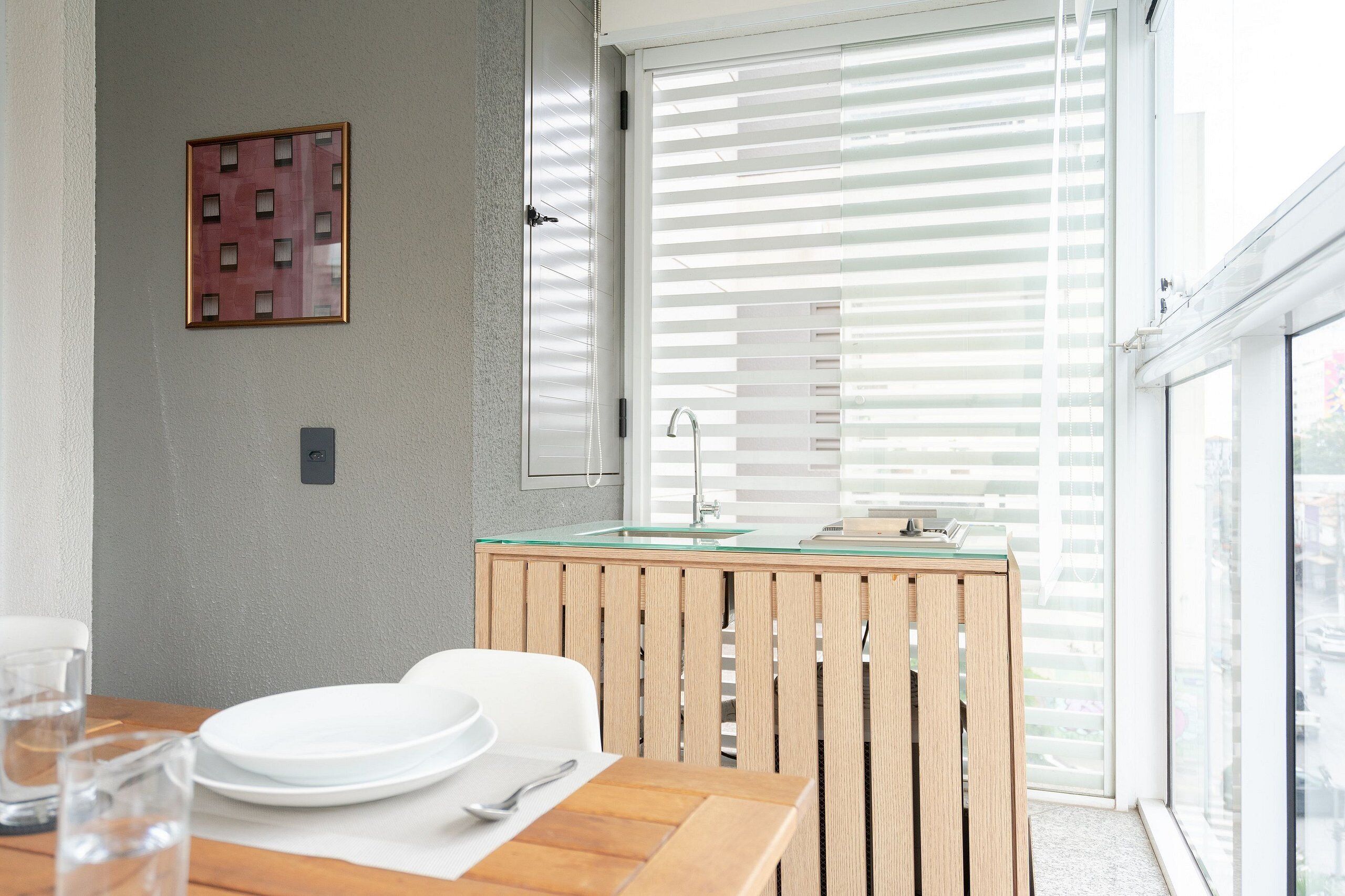 A modern kitchen with a wooden table, white plates, and a glass cabinet.