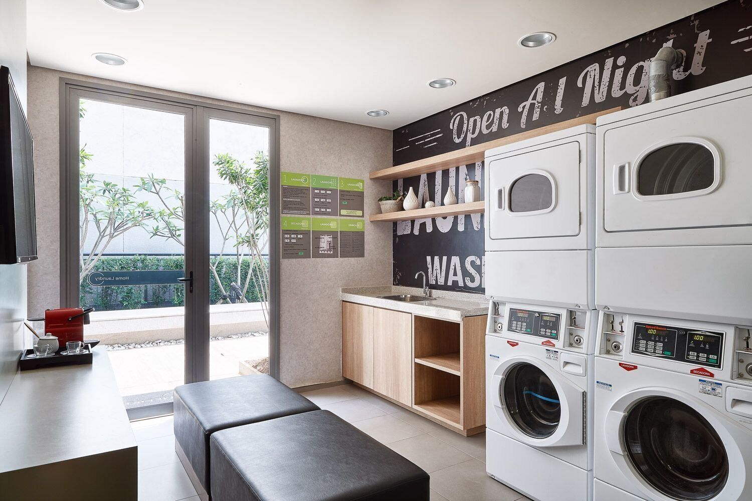 A modern kitchen with a built-in washer and dryer, a dining area with a bench, and a view through a glass door.