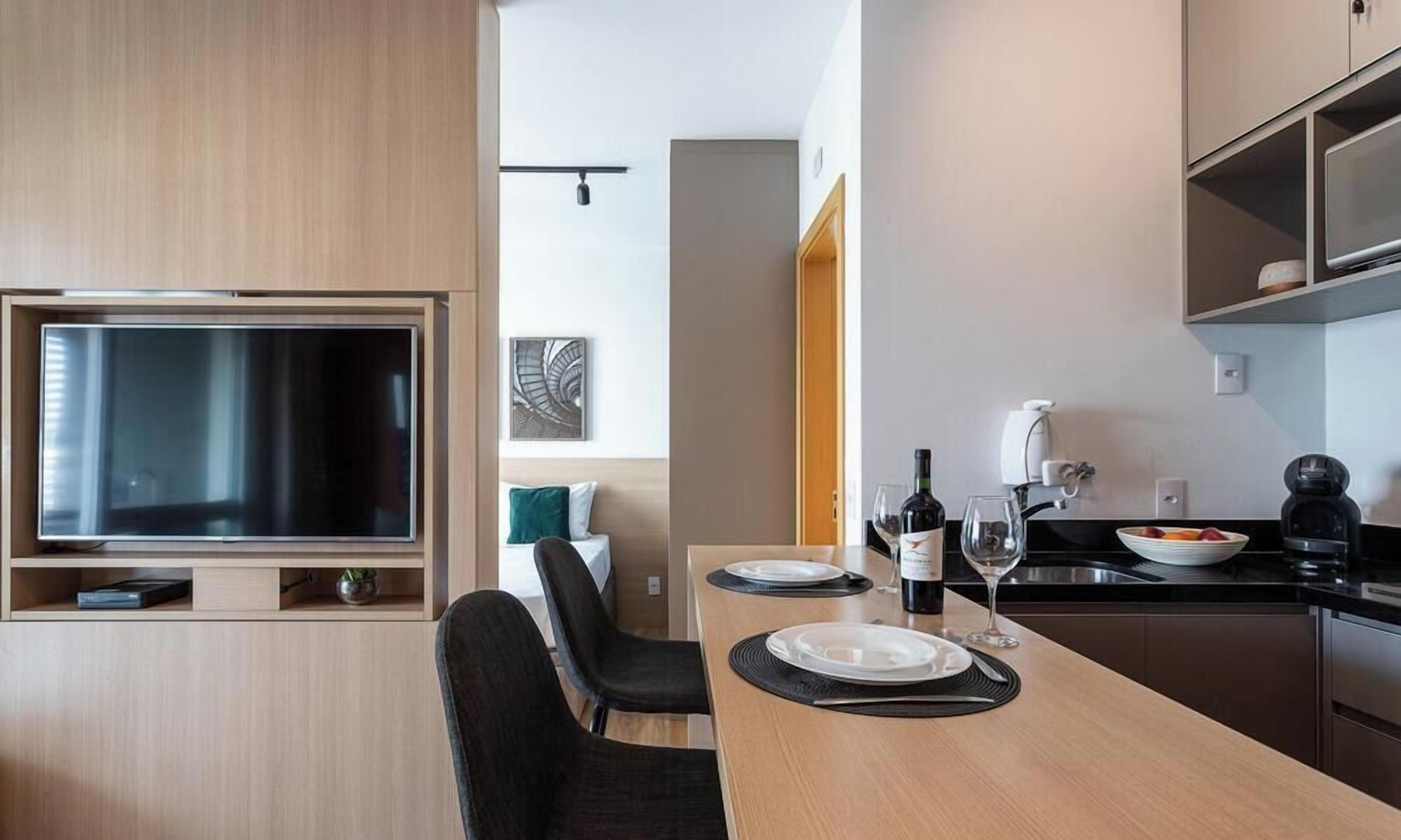 Une cuisine moderne avec un coin repas, un téléviseur à écran plat et une machine à café.