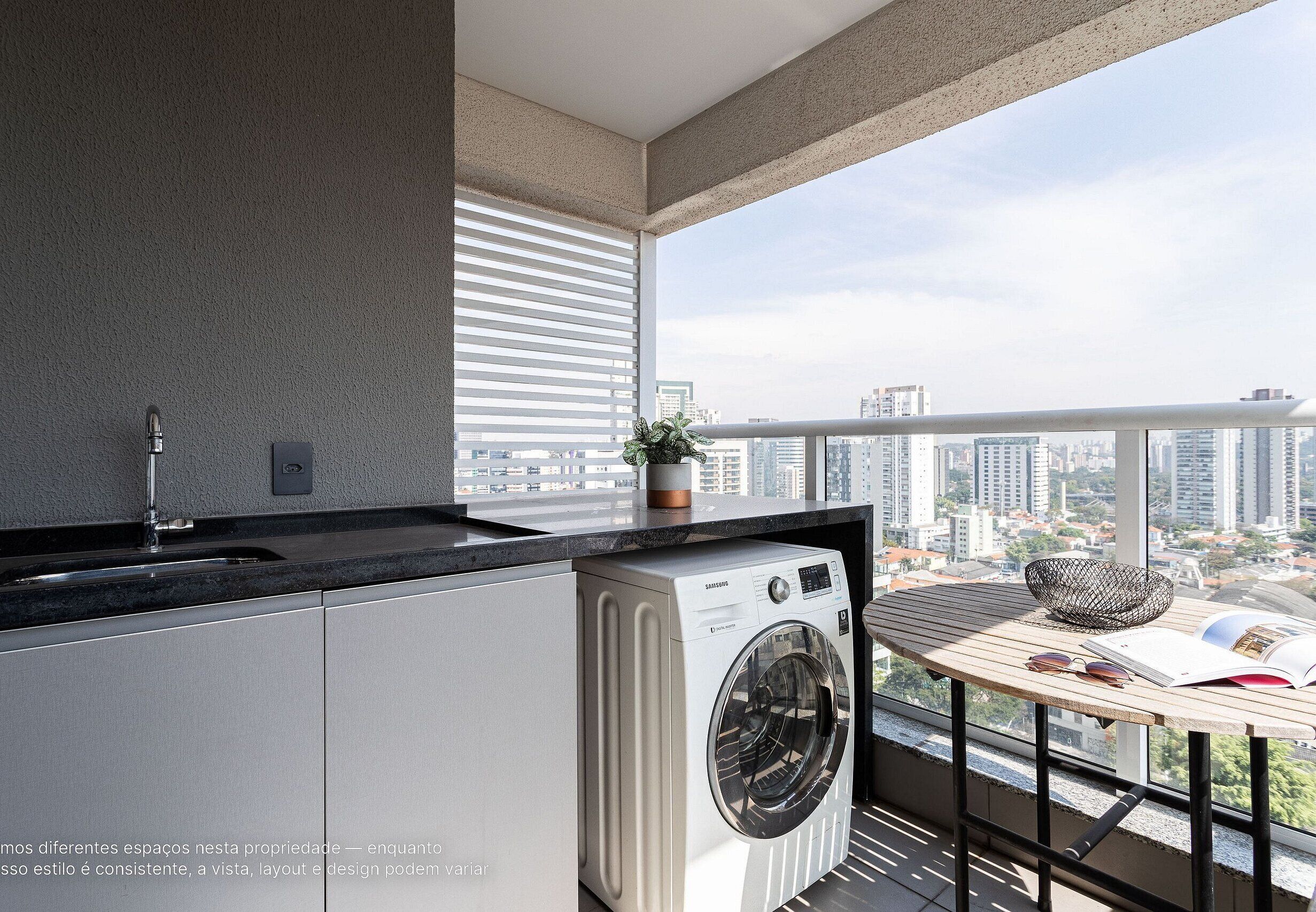 A modern apartment with a washing machine, a sink, a small table with a plant, and a view of the city.