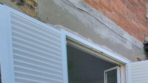 Una stanza con una porta socchiusa, un letto con copripiumino fantasia e un muro in mattoni.