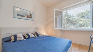 A bedroom with a bed, a window, a picture on the wall, and a chair.