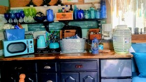 A kitchen with a microwave, kettle, and coffee maker on the counter, a water dispenser, and a shelf with glass containers and a box labeled 'SAPORI DITALIA'.
