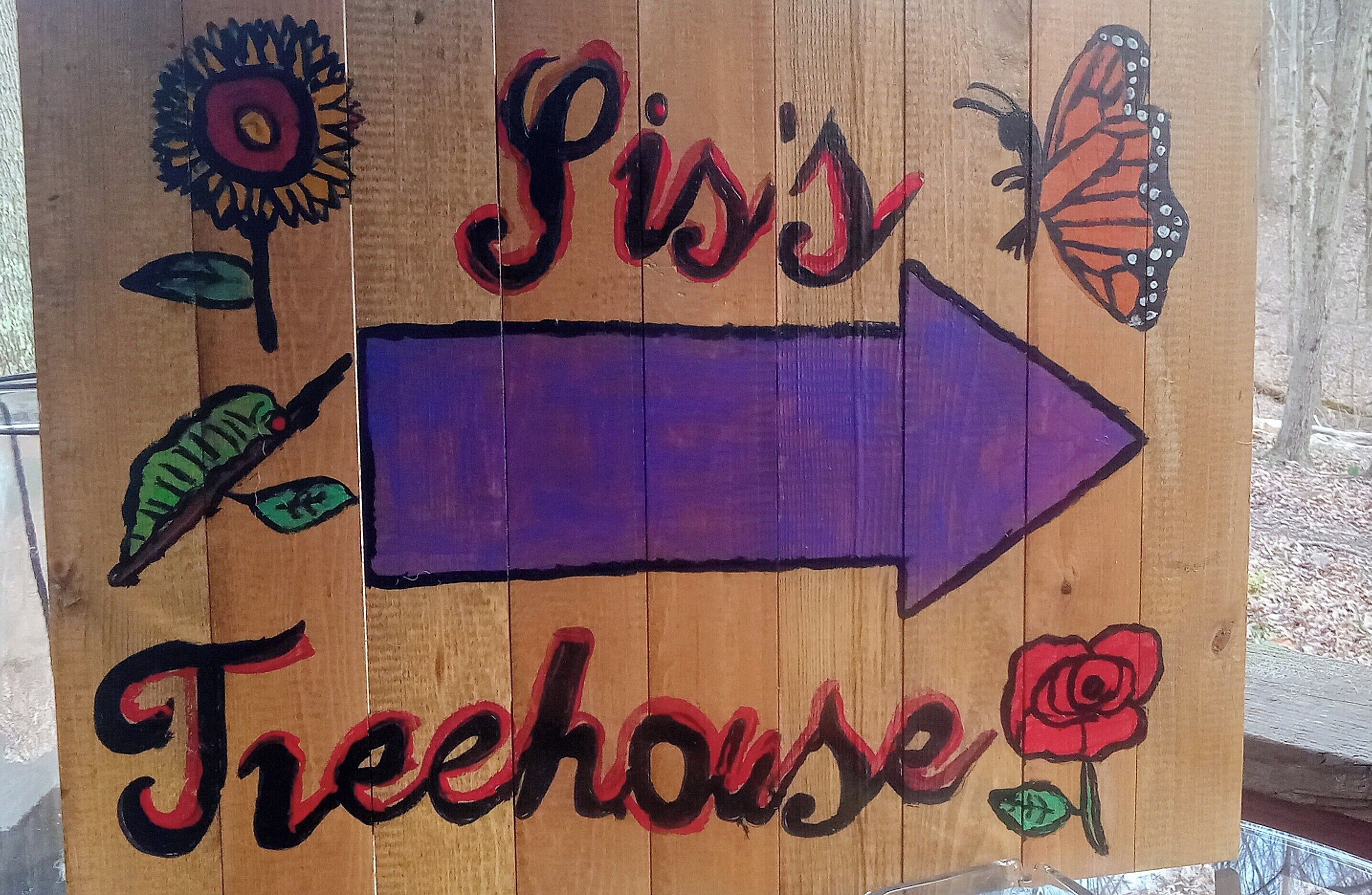 A wooden sign with 'Sis's Treehouse' written in cursive, an arrow pointing to the right, and illustrations of a sunflower, butterfly, leaf, and rose.