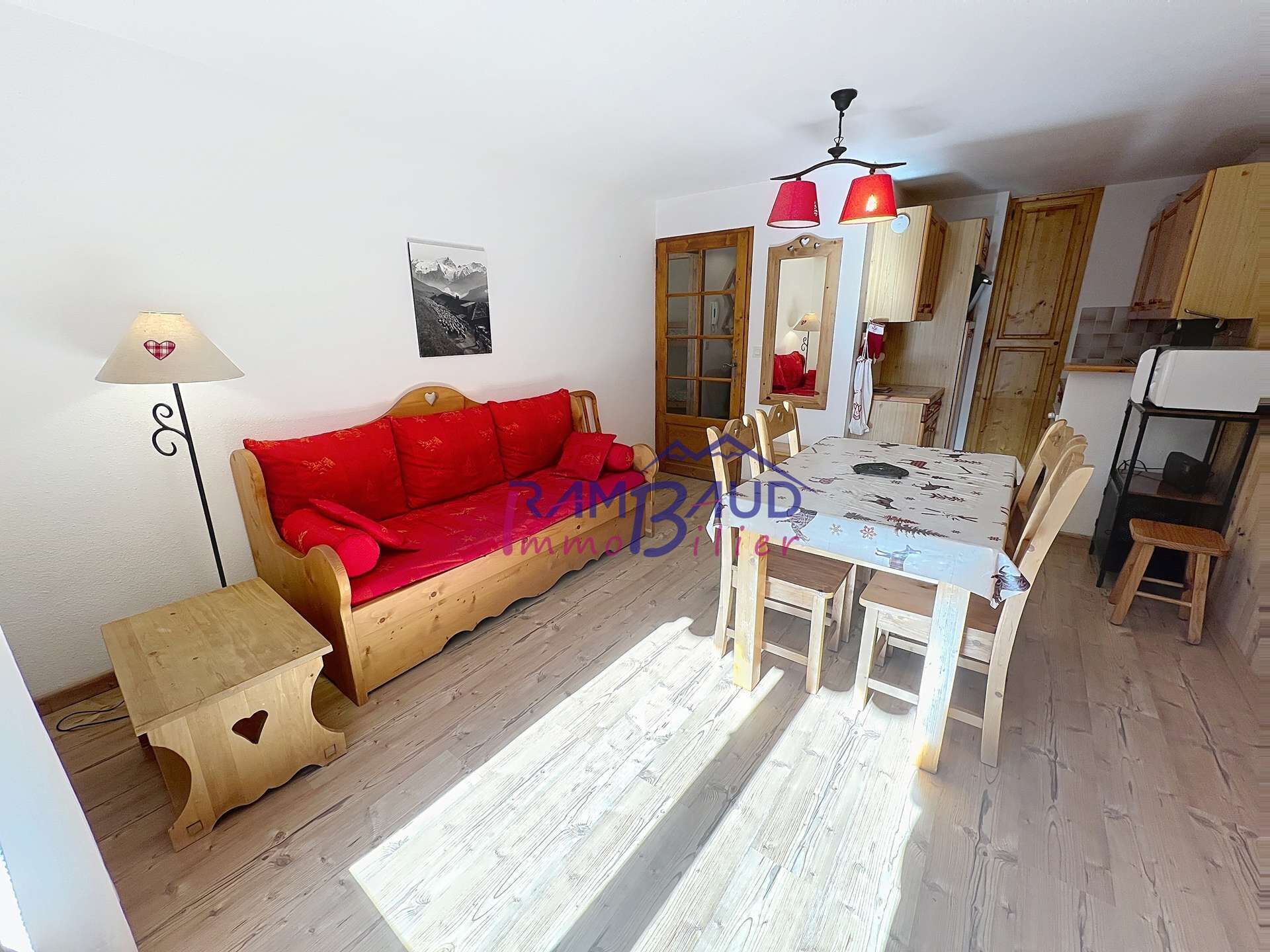 Ein gemütliches Zimmer mit einer Holzsofa, einem Esstisch mit Stühlen und einer kleinen Holzschrank.