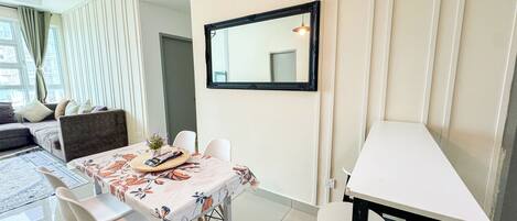 Un comedor con una mesa lista para dos personas, un sofá y un espejo en la pared.