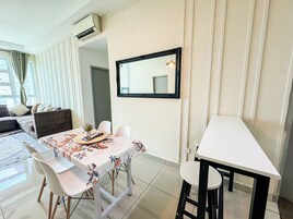 A dining area with a table set for two, a sofa, and a mirror on the wall.