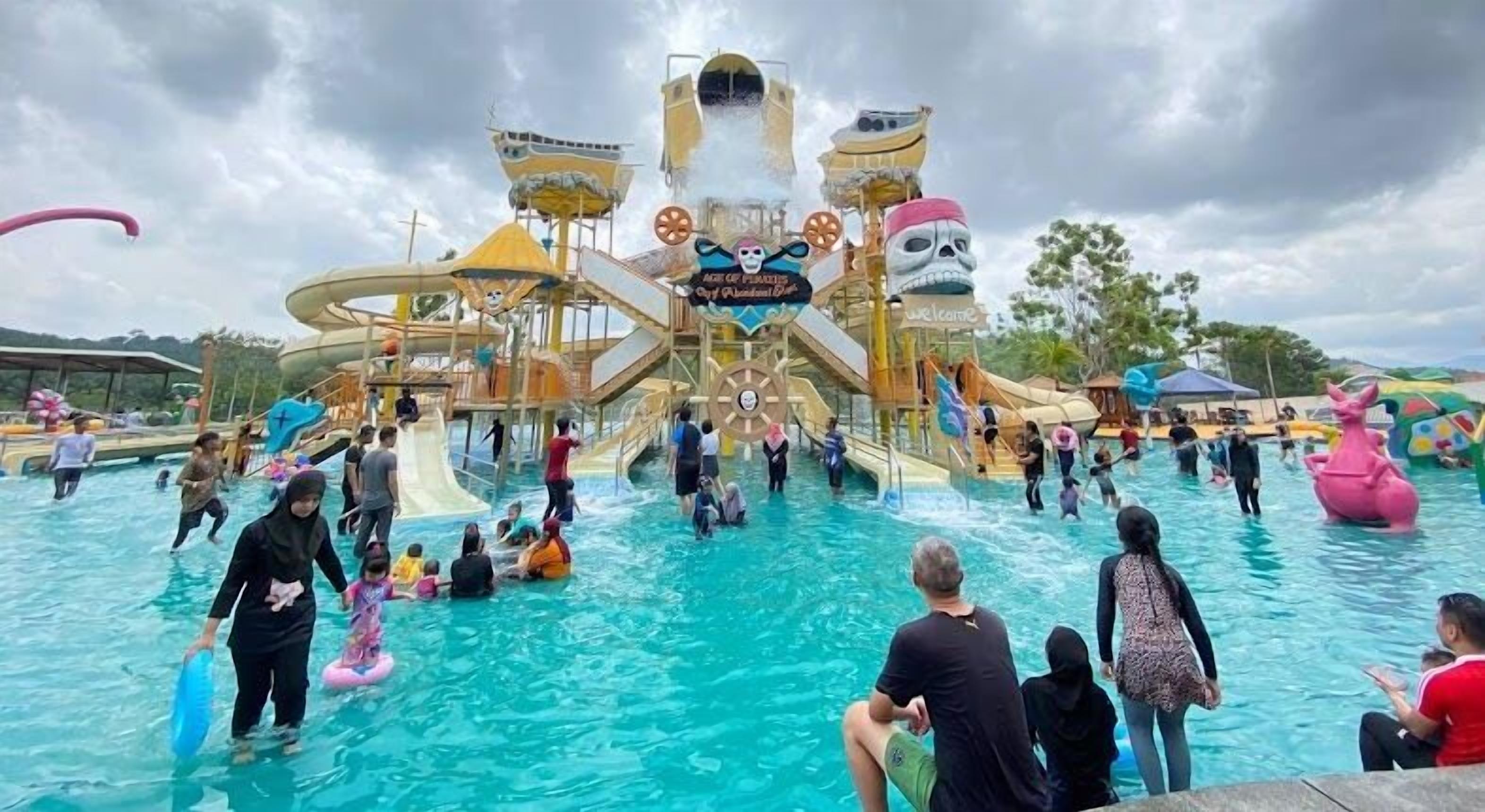 Ein Wasserpark mit mehreren Rutschen und Wasserspielen, darunter eine große Rutsche mit Totenkopfdarstellung an der Spitze.