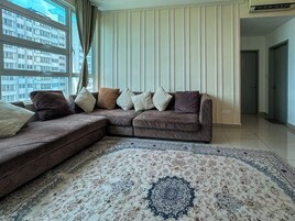 A living room with a sectional sofa, a patterned rug, and a view of a building through the window.