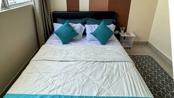 Habitación de hotel con cama, ropa de cama verde aguamarina y blanca, cabecero y vistas al exterior.