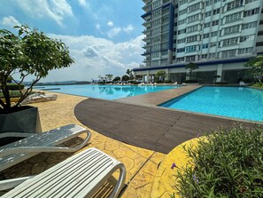 A swimming pool area with lounge chairs and a wooden deck. - Palmyra Residence (Kajang)