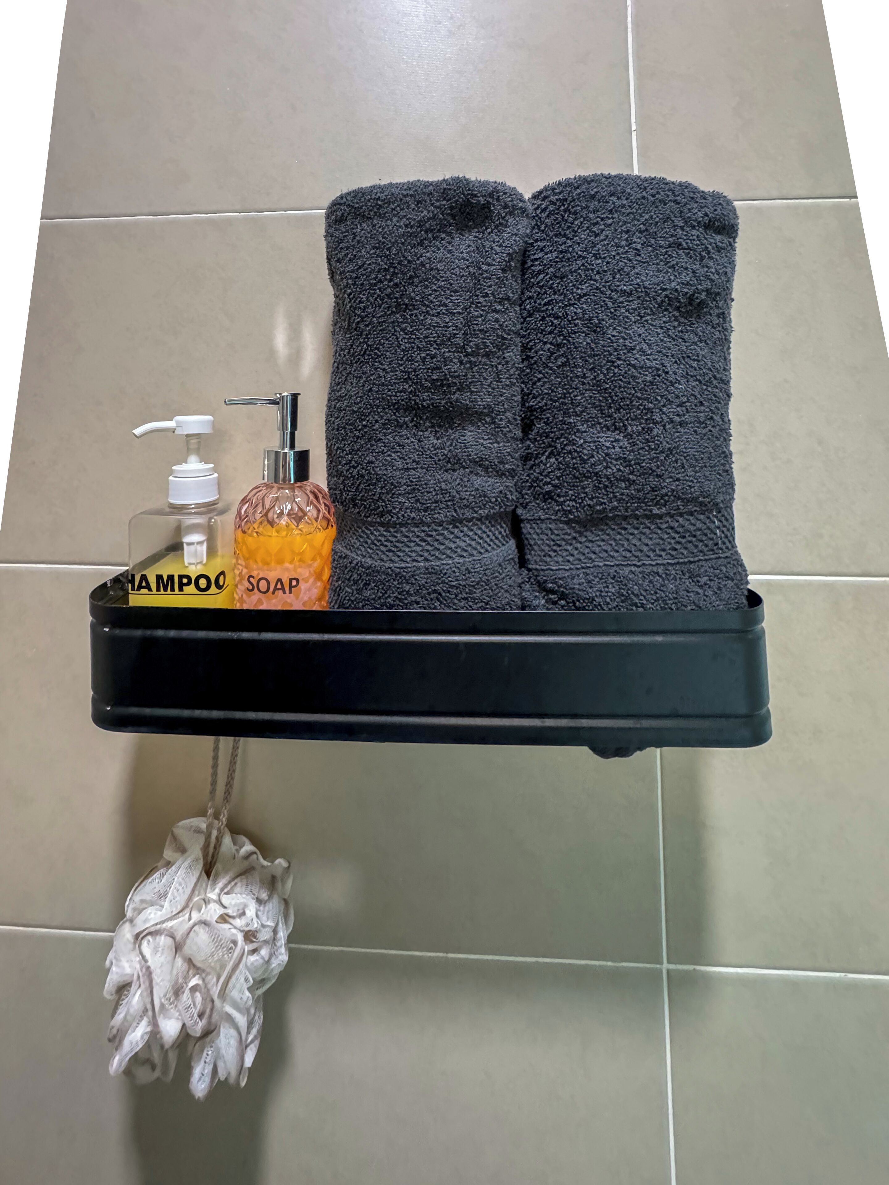 Un estante de baño con un dispensador de jabón negro, una botella de champú y un par de toallas.