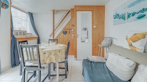 Una habitación acogedora con una mesa de comedor, sillas, un sofá, una escalera y obras de arte en las paredes.