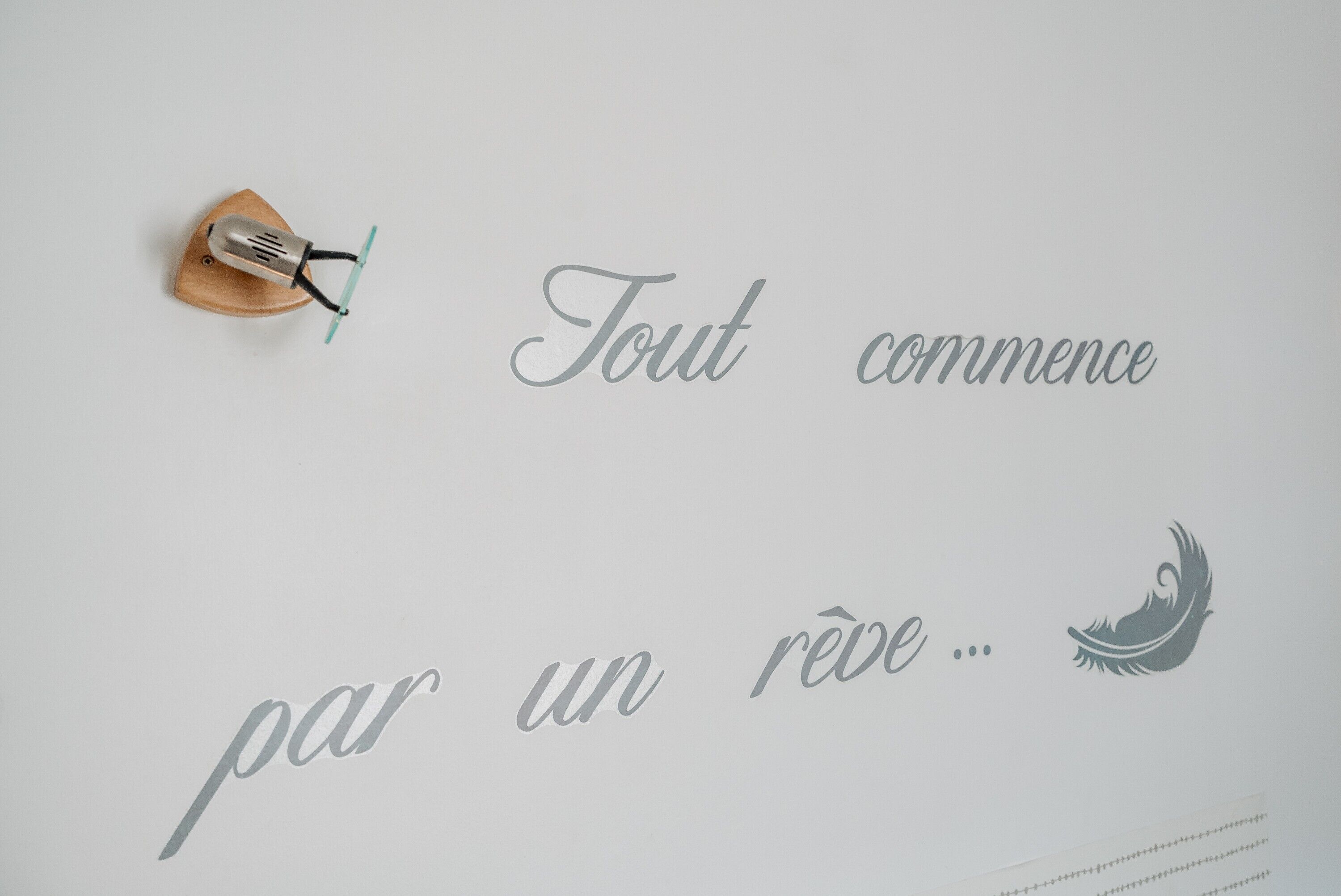 Een muur met de tekst 'Tout commence par un rêve...' en een klein object dat op een microfoon lijkt.