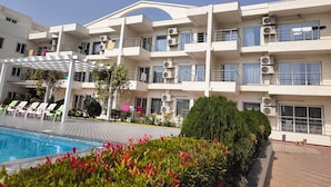 A multi-story hotel with balconies, air conditioning units, and a swimming pool. - Royal Gitanjali Resort &Spa (Kanthi)