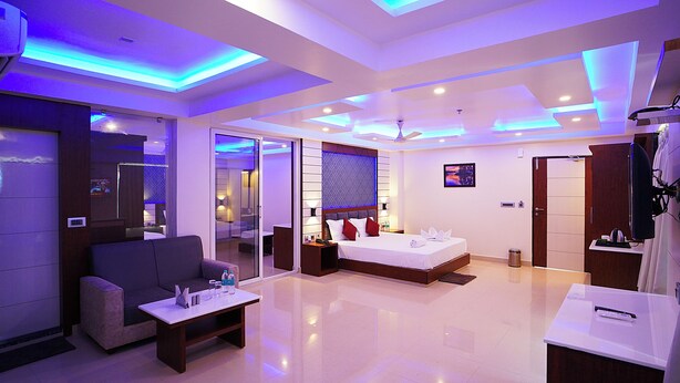 A modern hotel room with a sofa, a bed, a small table, and a TV. - Royal Gitanjali Resort &Spa (Kanthi)