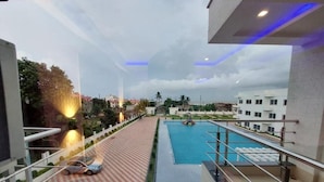 A modern hotel with a swimming pool, a covered outdoor area, and a view of surrounding buildings. - Royal Gitanjali Resort &Spa (Kanthi)