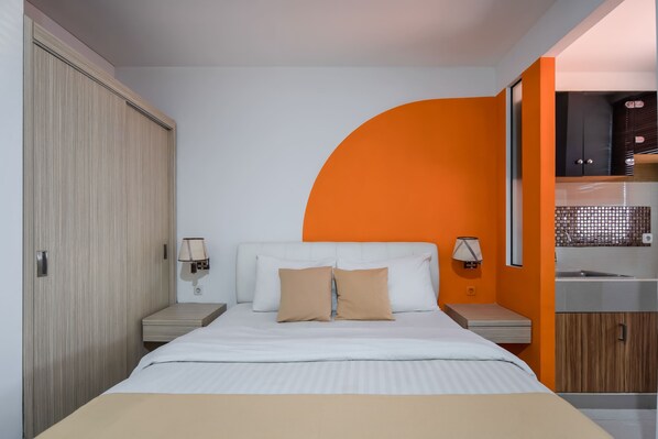 A hotel room with a bed, nightstands, a wardrobe, and a bathroom with a sink and mirror. - Cove Taman (Jakarta)