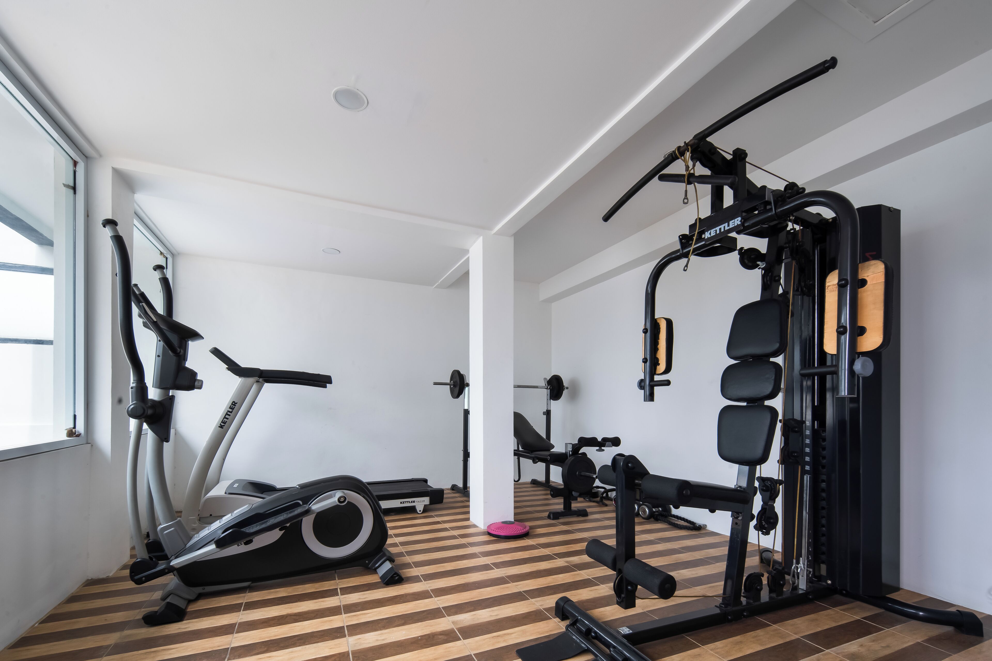 A gym with cardio machines, weightlifting equipment, and a wooden floor.