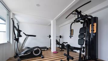 Un gimnasio con máquinas de cardio, equipo de levantamiento de pesas y suelo de madera.