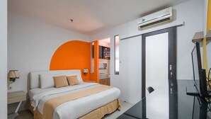 A modern hotel room with a bed, a desk, and an air conditioning unit. - Cove Taman (Jakarta)