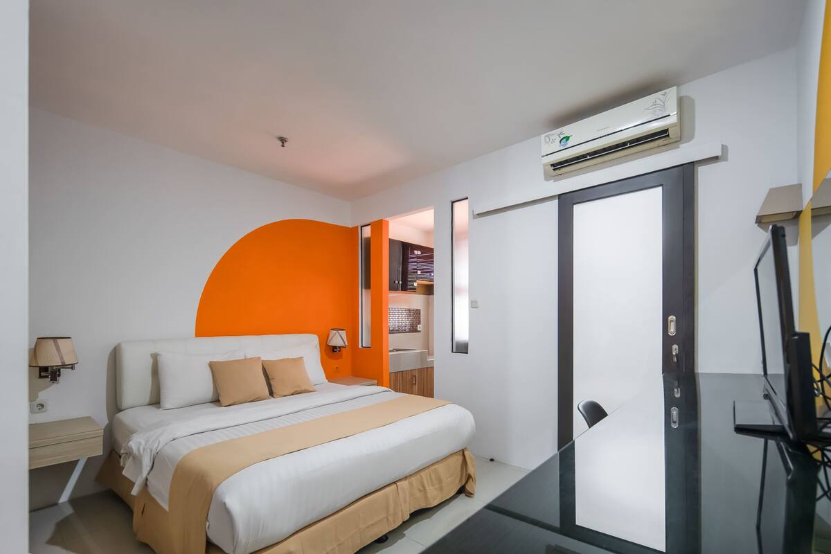 A modern hotel room with a bed, a desk, and an air conditioning unit.