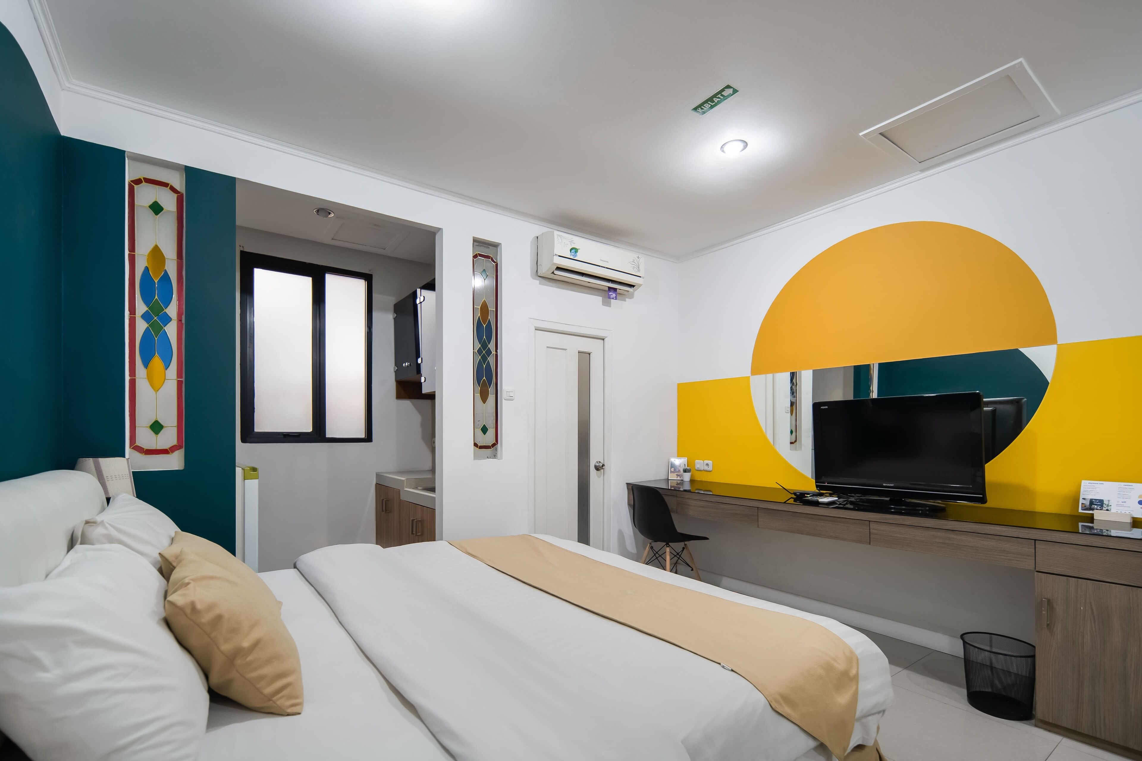 Une chambre d’hôtel avec un lit, un bureau doté d’une télévision et une salle de bain visible à travers une porte ouverte.