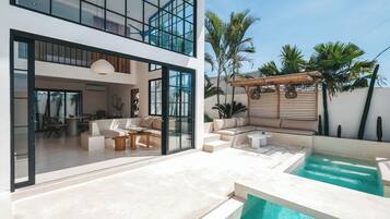A modern two-story house with a pool, outdoor seating, and a pergola.