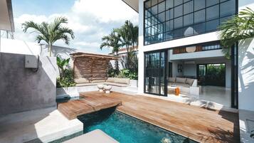 A modern house with a swimming pool, outdoor seating, and large windows.