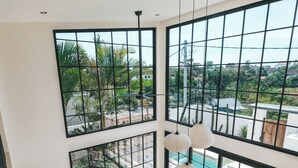 Un interior moderno con un área de descanso curvada, ventanas amplias y vista a una piscina.