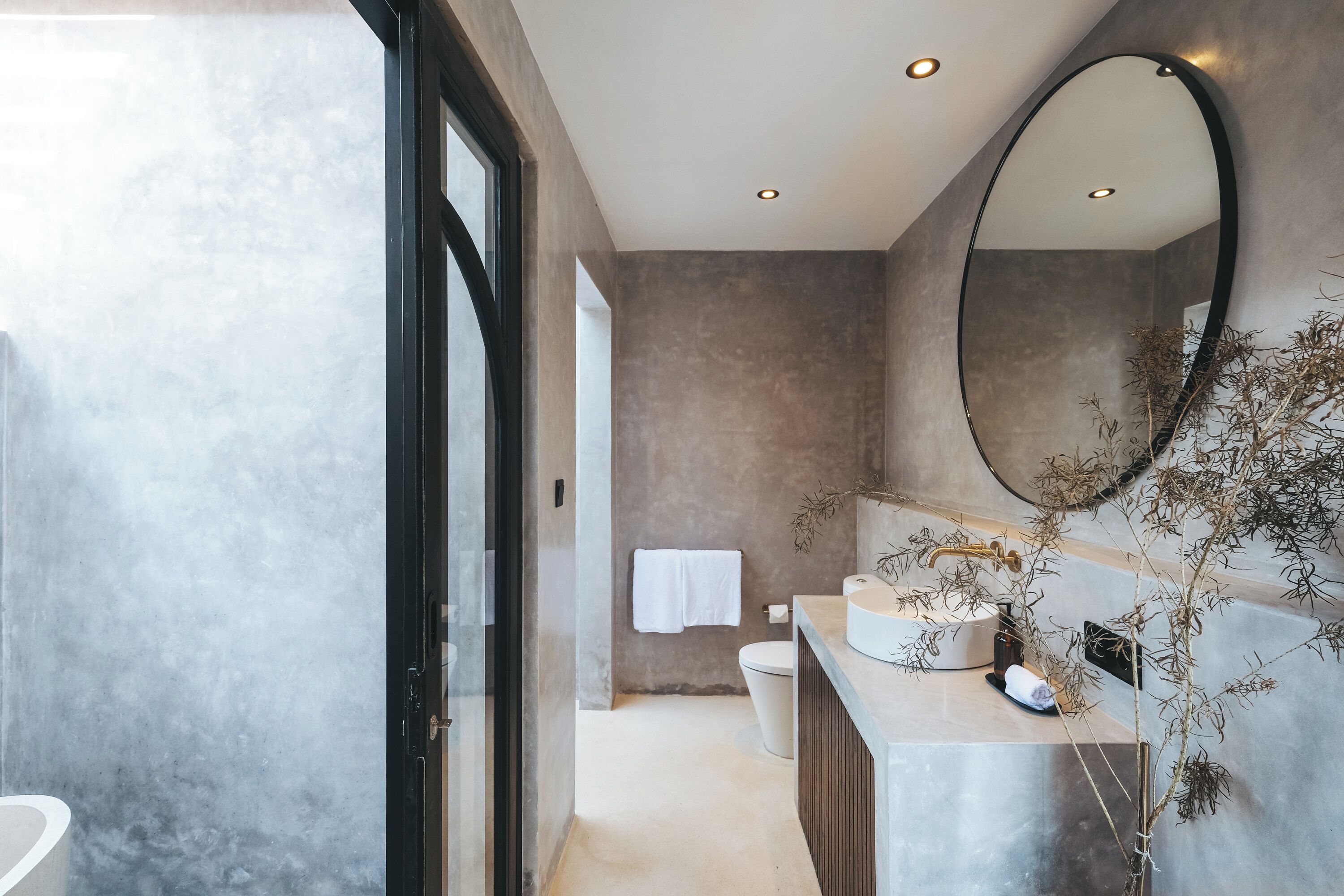 A modern bathroom with a large mirror, a sink, and a toilet.