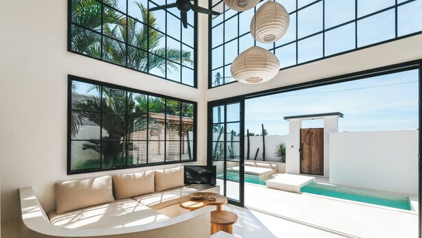 Un interior moderno con una zona de estar con asientos curvos, ventanas amplias y vista a la piscina.