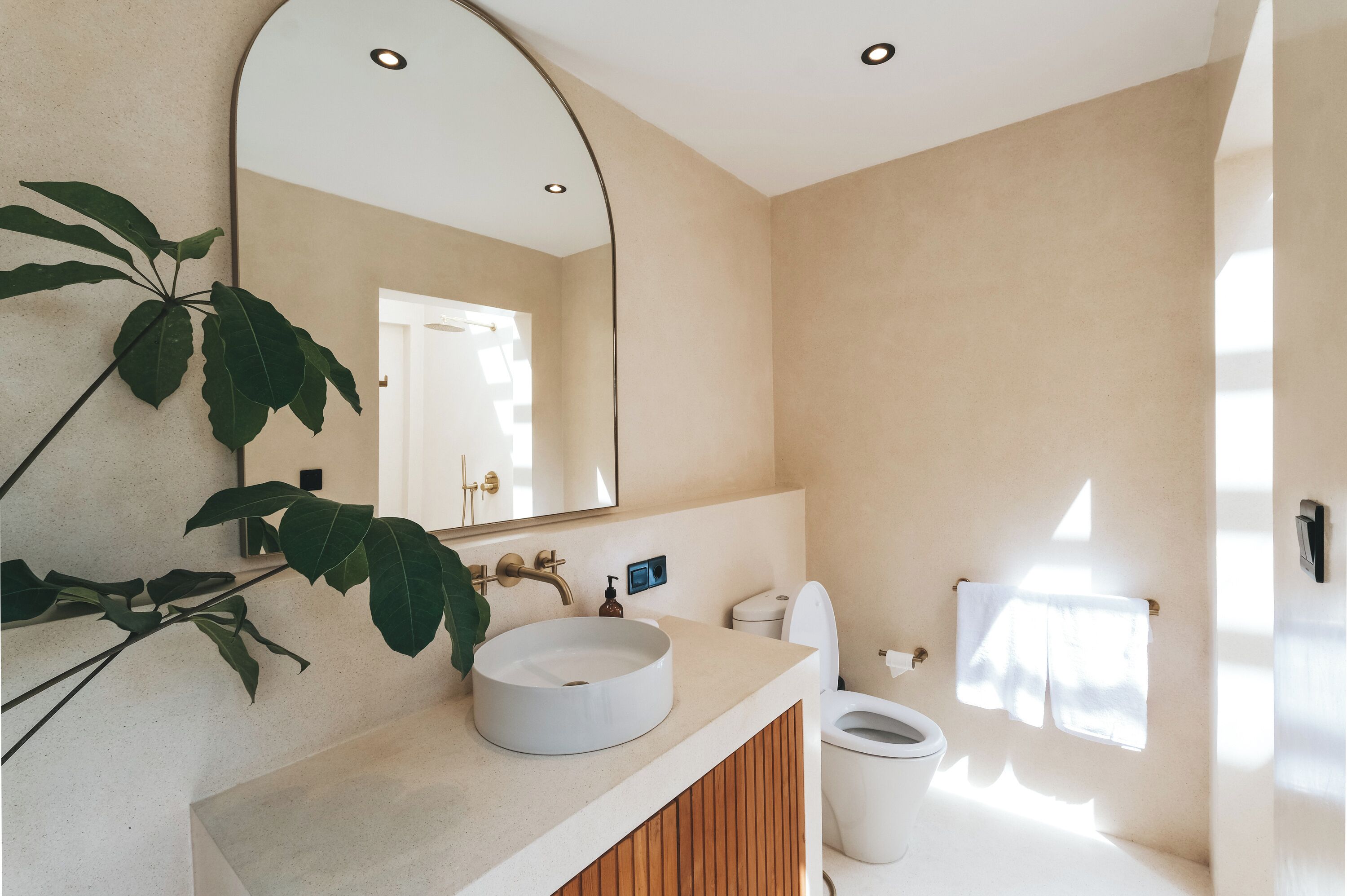 A modern bathroom with a round sink, a large mirror, and a toilet.