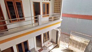 A two-story building with a balcony, a scooter, and a bicycle. - Hotel O Penginapan Hj Lilis Syariah (Sukabumi)