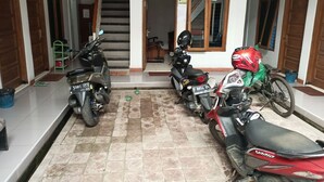 A covered parking area with three motorcycles parked in a row. - Hotel O Penginapan Hj Lilis Syariah (Sukabumi)