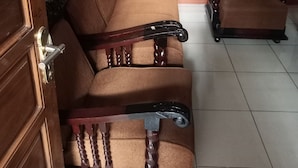 A room with a wooden door, a brown sofa, and a matching armchair. - Hotel O Penginapan Hj Lilis Syariah (Sukabumi)