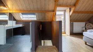 Quarto estilo loft moderno com claraboia, guarda-roupa embutido e um espaço de estar acolhedor.