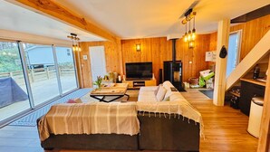 A cozy living room with a sofa, TV, and wooden walls.