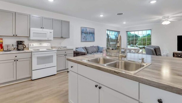 A modern kitchen with white cabinets, a stainless steel sink, and a built-in oven. - Eagle's Nest - Upscale Loft,Downtown,Close to GSU! (Statesboro)