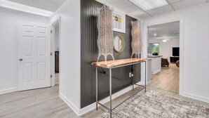 A modern interior with a dark accent wall, a wooden bench, and decorative mirrors. - Eagle's Nest - Upscale Loft,Downtown,Close to GSU! (Statesboro)