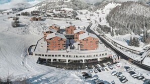 A snow-covered ski resort with multiple buildings, including a central hotel with a parking lot. - Catrina 3-Zimmer Premium Apartment by Interhome (Disentis)