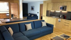 A modern living room with a sectional sofa, a dining area, and a kitchenette. - Catrina 3-Zimmer Premium Apartment by Interhome (Disentis)