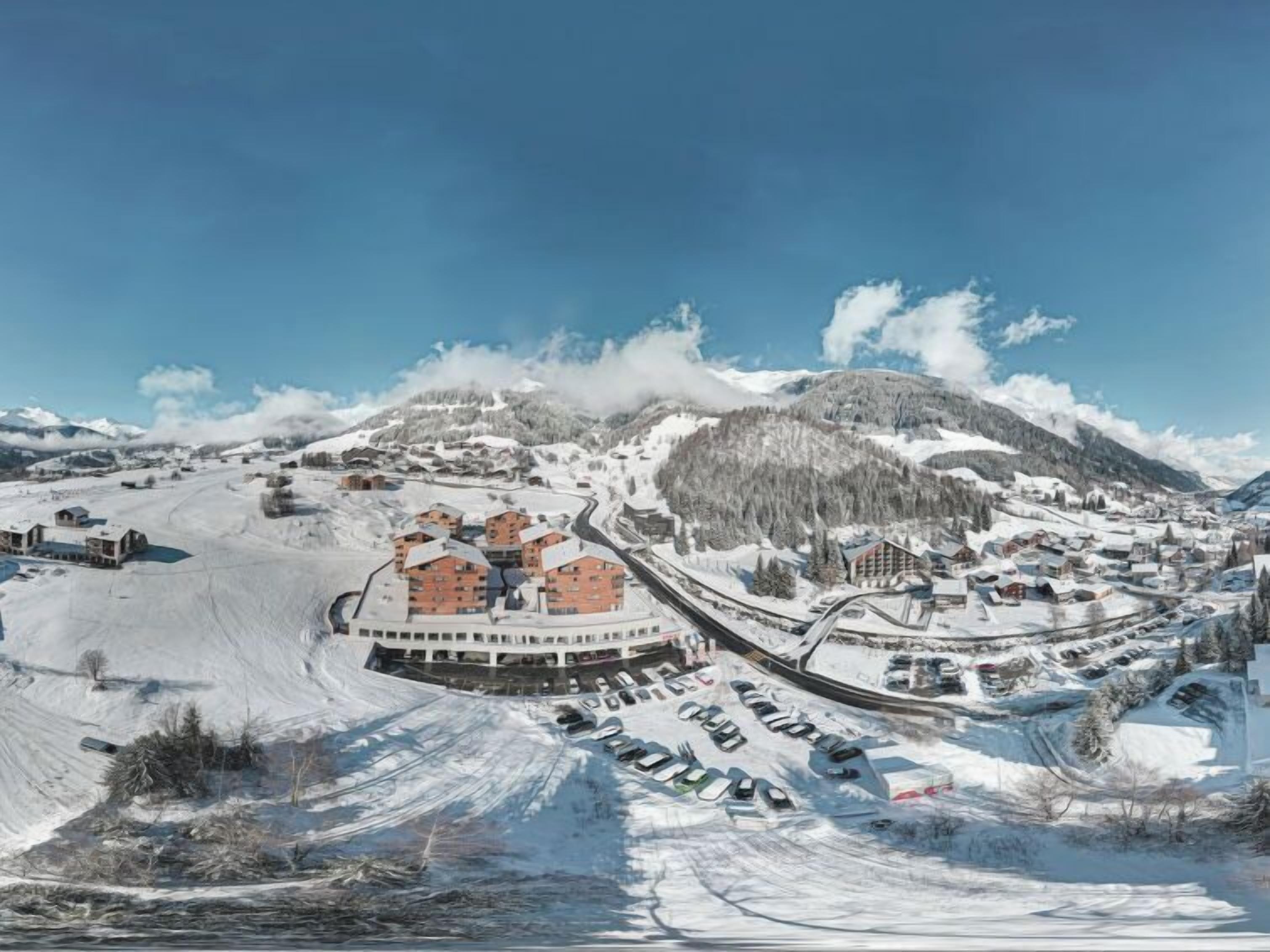 Un pueblo cubierto de nieve en la montaña, con un complejo central de varios pisos y un estacionamiento.