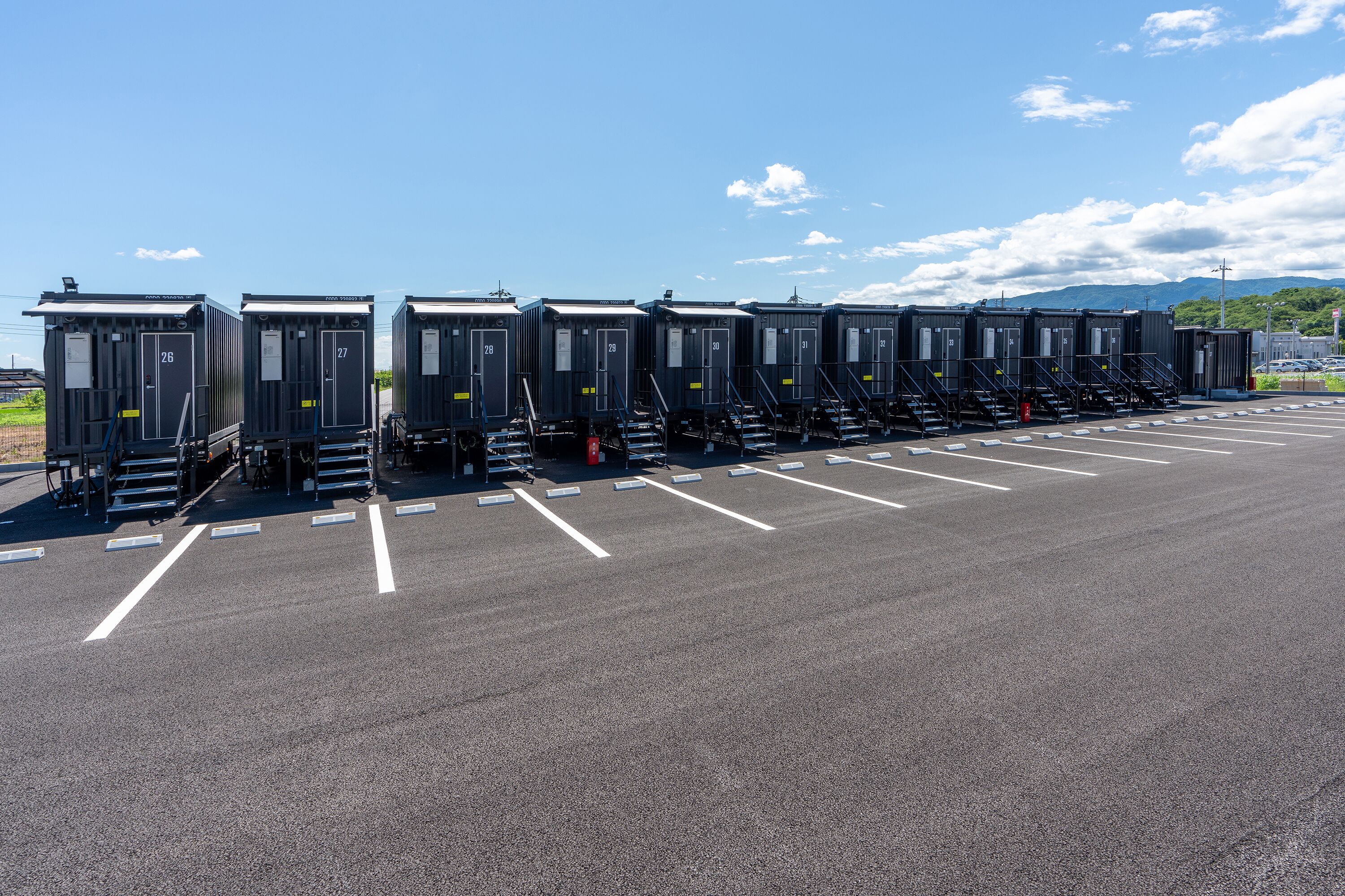 Portable restrooms lined up in a parking lot with clear markings.