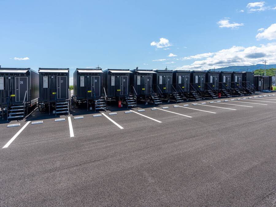 Portable restrooms lined up in a parking lot with clear markings.