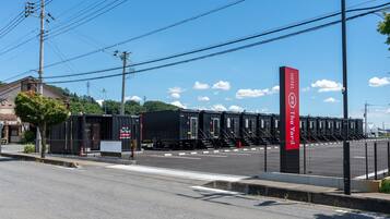 A hotel with a red sign, a parking lot, and a train station in the background.