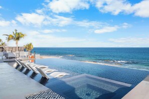 A infinity pool with a view of the ocean and palm trees.